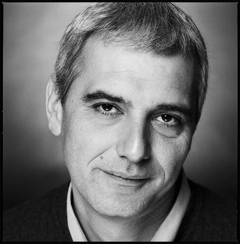 A black-and-white portrait of Mr. Cantet, with short, graying hair, gazing into the camera.
