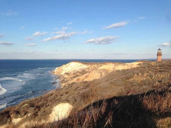 gay head cliffs and light house in aquinnah. The ocean is in the background, a redbrick light house on the cliffs to the right of the image on martha's vineyard in november