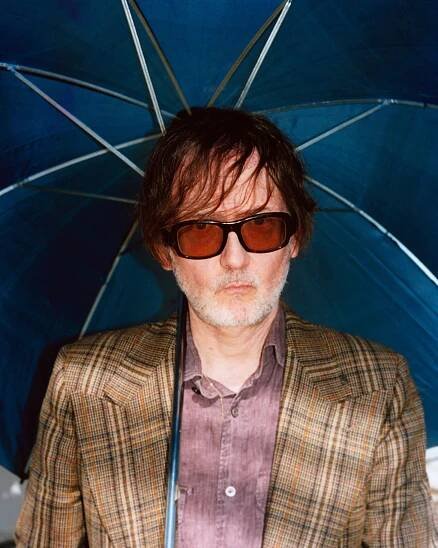 Jarvis Cocker holding an umbrella.
