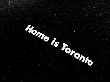 a close up of a black surface with the words home is toronto