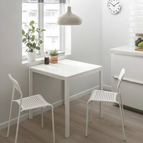 Malý bílý stůl a židle ADDE, moderní, minimalistický design. Obklopen kuchyňským dekorem, vhodný pro malé prostory.