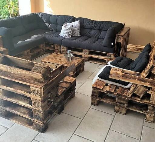 a living room filled with furniture made out of wooden pallets and black leather couches