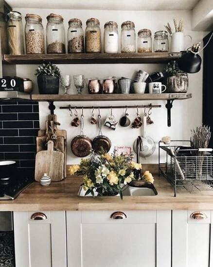a kitchen with lots of pots and pans on the shelf above the sink,