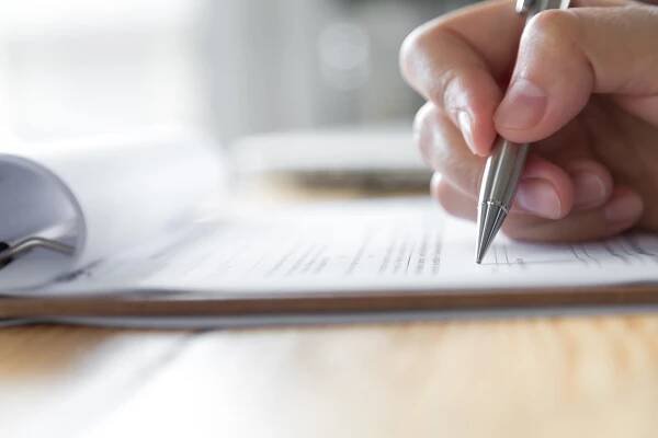 Hand with pen over application form