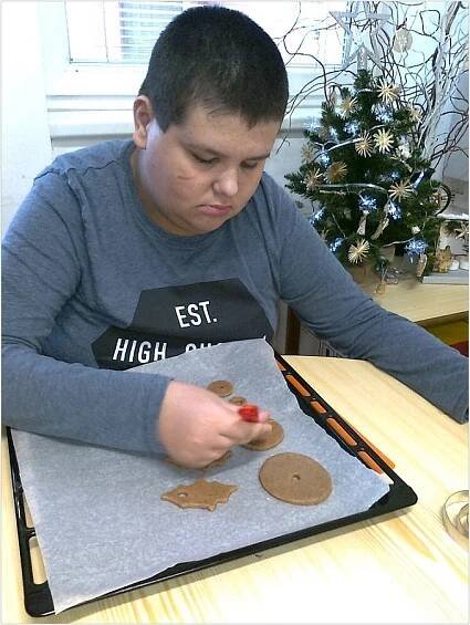 Žák potírá vajíčkem perníčky na plechu