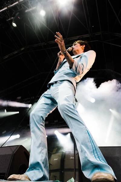 Justin Hawkins of The Darkness at Brownstock festival. He is in a pale blue suit and singing. Justin Hawkins Rides Again.