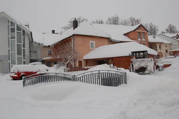 a yard covered in snow with houses and cars at Penzion Markus - Pivovar - Brewery Frymburk in Frymburk