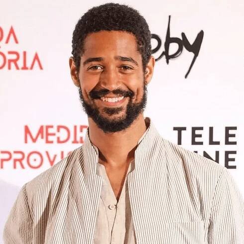 Alfred Enoch with a subtle fro and facial hair