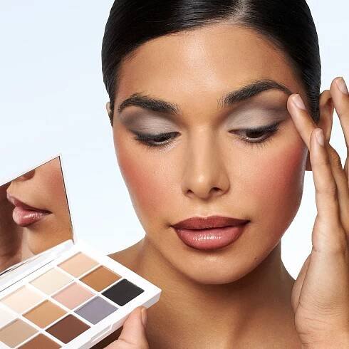 A woman holding a compact mirror with a white powder compact makeup by Mario.