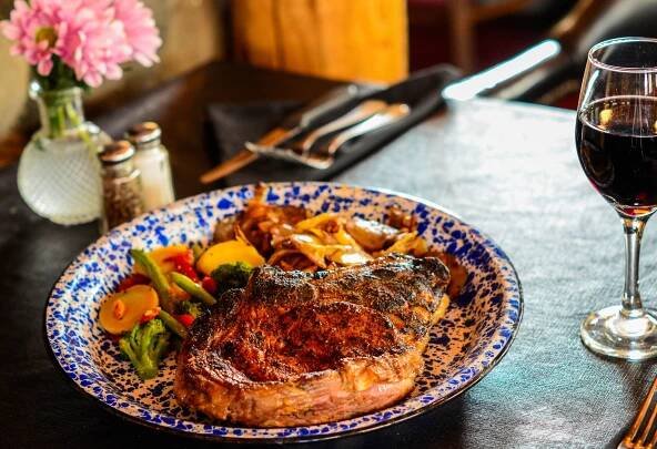A plate of food with a steak and vegetables on a table.