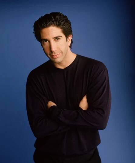 a young man with his arms crossed posing for a photo in front of a blue background