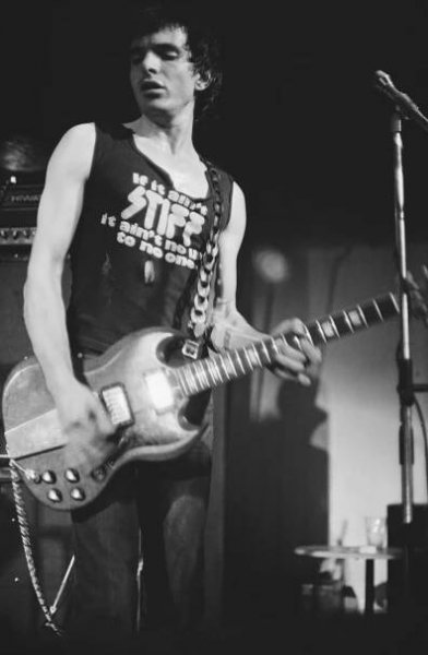 Brian James of The Damned performing on stage, playing guitar.