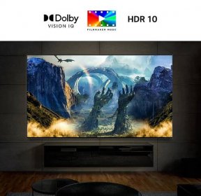 Ein Grossbildfernseher, der an einer Wand in einem dunklen Raum angebracht ist. Der Bildschirm zeigt eine Fantasy-Szene mit einem Drachen, der Feuer spuckt.