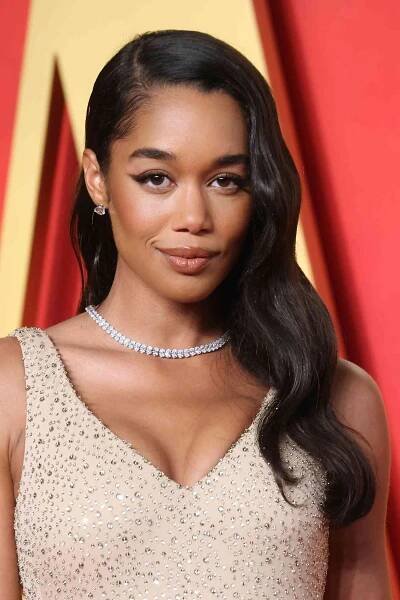 Laura Harrier wearing a deep center part with soft waves.