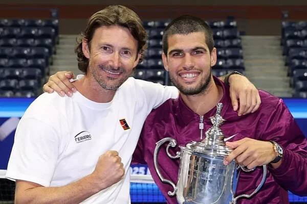 Carlos Alcaraz of Spain poses with his trophy next to his coach Juan Carlos Ferrero after defeating Jannik Sinner of Italy during their Men's Singles Final match on Day Fifteen of the 2025 US Open at USTA Billie Jean King National Tennis Center on September 07, 2025 in New York City. 