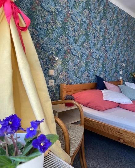 a bedroom with a bed and a chair and flowers at Penzion Slunečnice in Dvůr Králové nad Labem