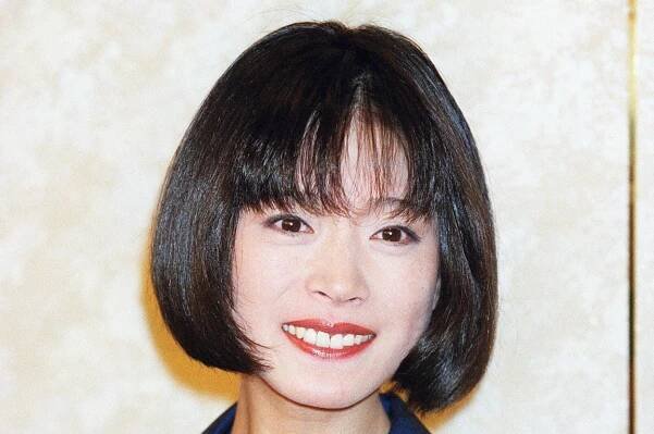 ショートヘアの女性がネイビーのブラウスを着て笑顔でポーズをとっています。