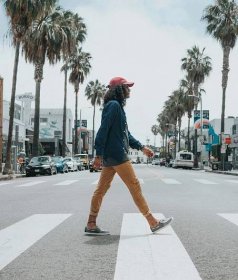 man wearing red cap crossing street