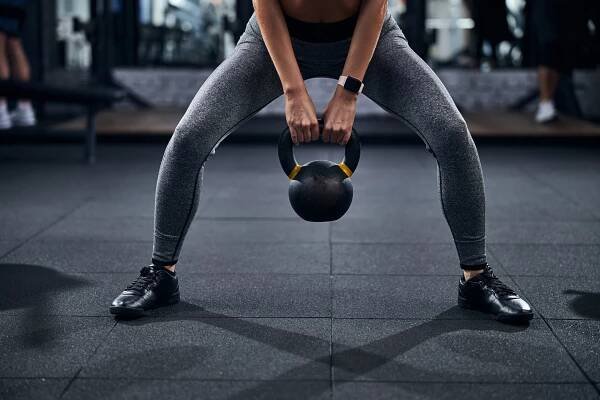 Osoba s kettlebell dělá sumo squat — Stock obrázek