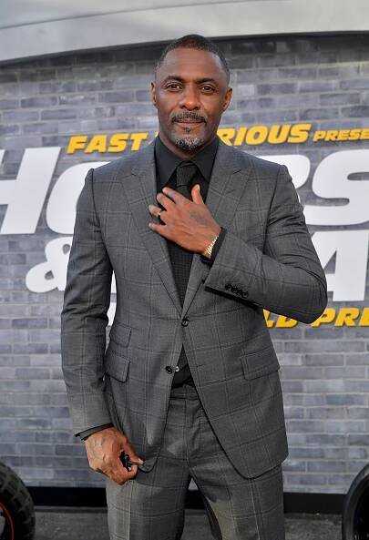 Image may contain Idris Elba Blazer Clothing Coat Jacket Formal Wear Suit Person Standing Adult and Accessories