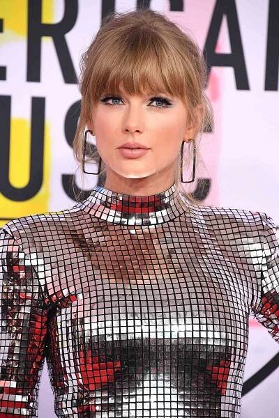 Taylor Swift with soft blonde bangs and face-framing tendrils while wearing a metallic gown