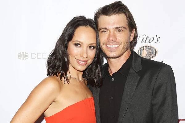 Cheryl Burke and Matthew Lawrence smiling on a red carpet.