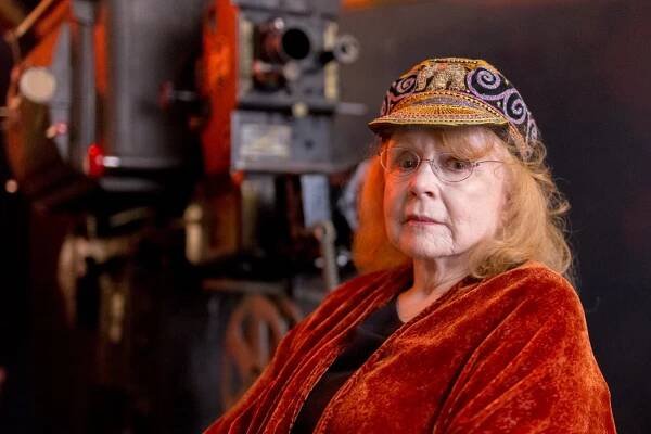 Piper Laurie in an orange robe and colorful cap.