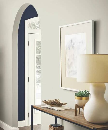 A hallway leading to another room, with an entryway table and a lamp. The walls are painted in Repose Gray by Sherwin Williams