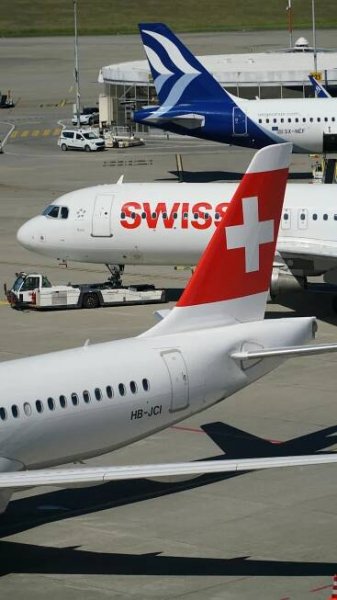 Free View of Swiss airplanes at Zurich Airport gate, showcasing modern aviation. Stock Photo