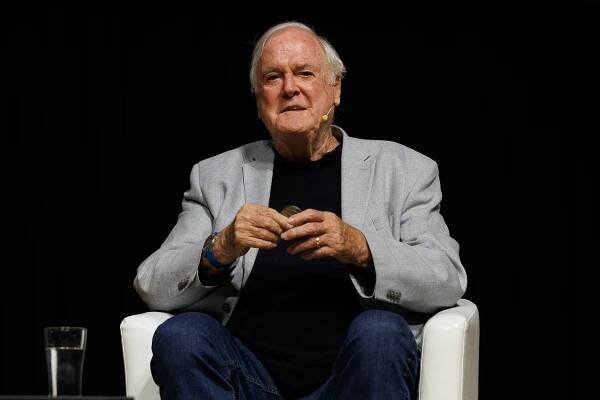 John Cleese holding a medal.
