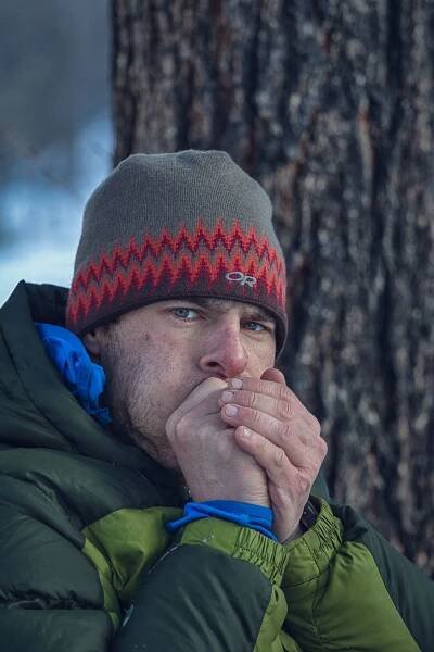 Gregg Treinish pauses from lacing his boots to warm his fingers on a frigid morning.