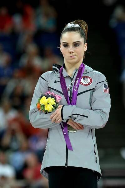 Young woman scrunches her mouth as she holds a small bouquet of flowers and folds her arms.