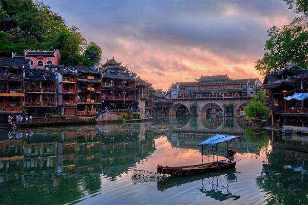 Chinese tourist attraction destination - Feng Huang Ancient Town (Phoenix Ancient Town) on Tuo Jiang River illuminated at night. Hunan Province, China