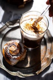 straw in glass of maple cream cold brew with cinnamon roll on silver plate