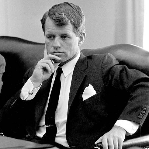 Robert Kennedy sits pensively with his hand on his face