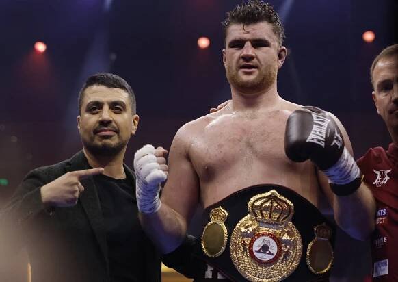 Johnny Fisher celebrates a boxing victory, wearing a championship belt.