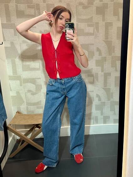 Woman wears red top, blue jeans and red trainers