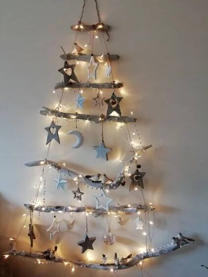 a christmas tree made out of branches with lights on it and stars hanging from the top