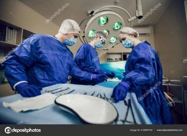 Portrét týmu chirurgů v práci. Na pacientovi začínají operovat tři lékaři v lékařských maskách. Lékaři v chirurgii, léčbě a medicíně