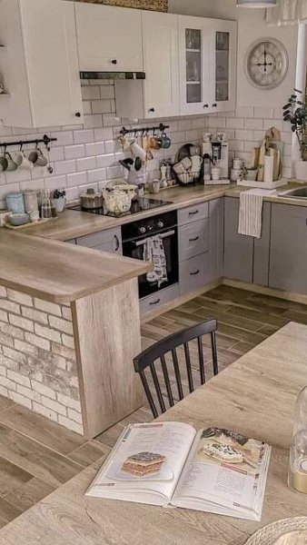 an open book sitting on top of a wooden table next to a kitchen sink and stove