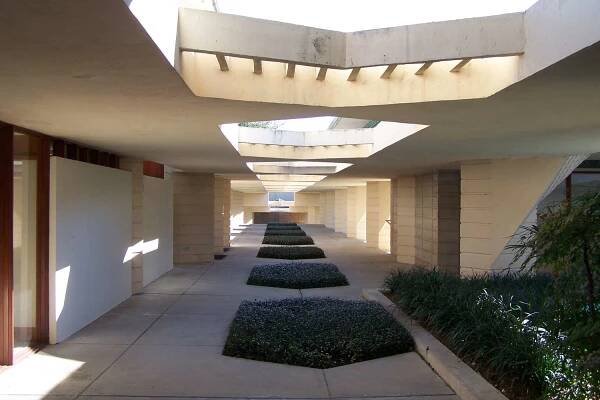 white concrete esplanade, partially covered walkway with vegetation