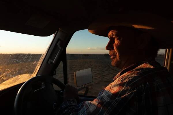  James "Dude" Kidd drives his vehicle across his property at dusk. 