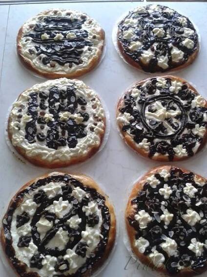 six cookies with white and black toppings on top of a cookie sheet covered in icing