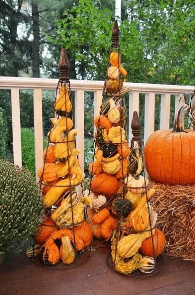 pumpkins and gourds are arranged on the porch