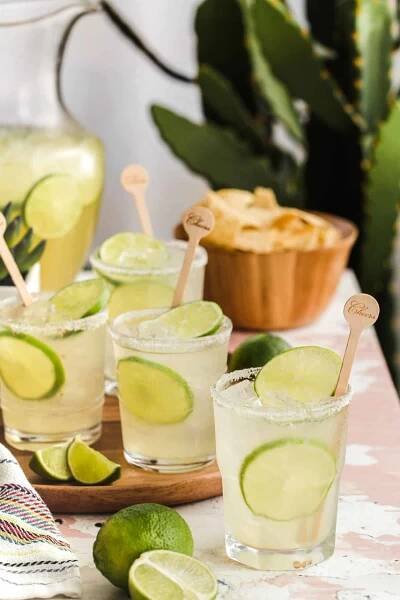 rustic table with pitcher drink and full glasses garnished with limes.