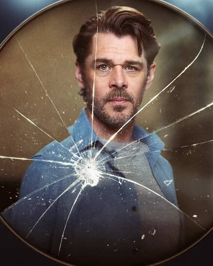 Portrait of Kenny Doughty as Chris, seen through a cracked circular mirror.