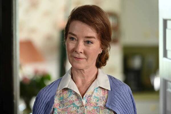 Valerie Mahaffey indoors wearing a floral top and cardigan