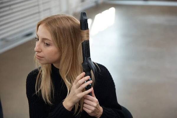 A person using the Bio Ionic Long Barrel Curling Iron on their hair