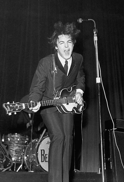 a man in a suit and tie playing an electric guitar while singing into a microphone