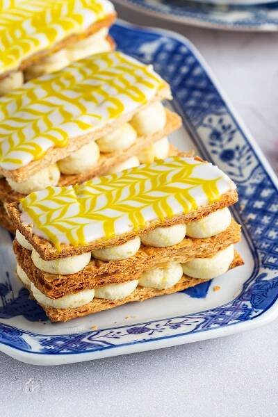 A close up shot of eggless mille feuille with white chocolate saffron yogurt cream placed in a blue tray